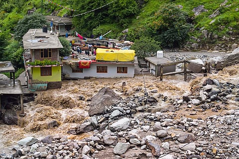 A damaged property is seen alongside a swollen Beas River, following a recent cloudburst, in Kullu district